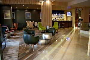 a lobby with green chairs and a bar at Hotel Golden Tulip Varna in Varna City