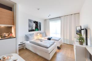 a white bedroom with a bed and a sink at SMARTments business Berlin Karlshorst in Berlin