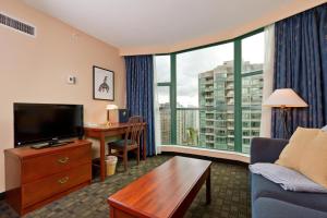 a living room with a tv and a large window at Rosedale on Robson Suite Hotel in Vancouver