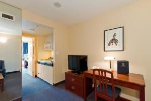 a room with a desk with a television and a kitchen at Rosedale on Robson Suite Hotel in Vancouver