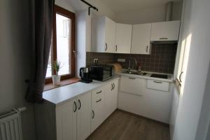 eine kleine Küche mit weißen Schränken und einem Fenster in der Unterkunft Penzion U Zamku in Jaroměřice na Rokytné