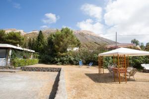 eine Terrasse mit einem Tisch, einem Sonnenschirm und Stühlen in der Unterkunft Titina Village Porto in Vulcano