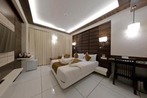 a bedroom with a bed and a desk and a television at Hotel Silver Heights in Ahmedabad