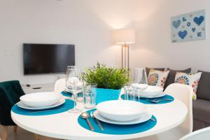 een witte eettafel met borden en wijnglazen bij Peña City Center Apartment in Málaga