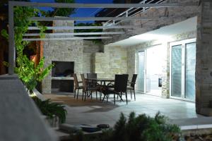 patio ze stołem, krzesłami i kominkiem w obiekcie Beachfront Apartments - Villa Vita w mieście Stara Novalja