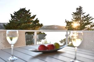 two glasses of wine and a bowl of fruit on a table at Beachfront Apartments - Villa Vita in Stara Novalja