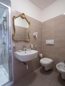 ein Badezimmer mit einem Waschbecken, einem WC und einem Spiegel in der Unterkunft Hotel Lieto Soggiorno in Assisi