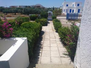 una pasarela de piedra en un jardín con flores rosas en Afantou beach house, en Kolymbia