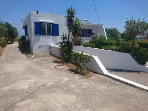 una casa blanca con una valla al lado de una entrada en Afantou beach house, en Kolymbia