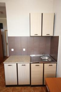 a kitchen with wooden cabinets and a sink at Apartments DEA in Bar