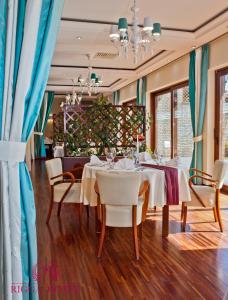 弗瓦迪斯瓦沃沃的住宿－Hotel Rigga Willa Łucja，一间设有白色桌椅和蓝色窗帘的用餐室