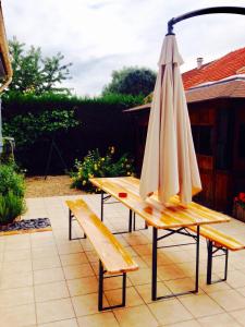 a wooden bench with an umbrella on a patio at Grande Rue House Disneyland Paris in Magny-le-Hongre