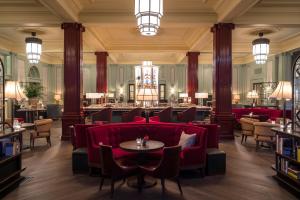 a restaurant with a red couch and tables and chairs at The Gleneagles Hotel in Auchterarder