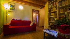 sala de estar con sofá rojo y estante para libros en B&B Al Gatto Nero, en Borgo