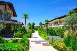 a walkway between two buildings with palm trees at Sky Fort Garda View in Sirmione