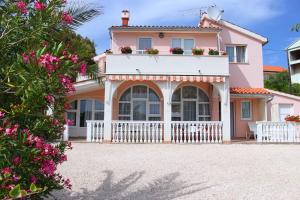 a pink house with a white fence and flowers at Apartments Tonka in Primošten