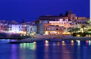 uitzicht op een stad 's nachts met het water bij Residenza Carone in Porto Cesareo