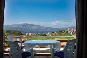 a table and chairs on a balcony with a view of the mountains at House Baglija in Lumbarda