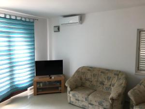 a living room with a chair and a flat screen tv at Apartments Volarevic in Blace