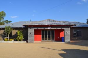 un edificio rosso e nero con una porta rossa di La Signature Guest house a Francistown