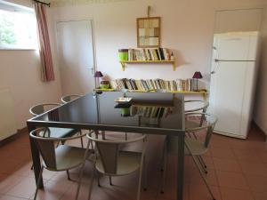 a dining room table with chairs and a refrigerator at La Closerie in Saint-Nizier-le-Bouchoux
