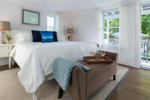 West Neck Guesthouse في Shelter Island Heights: غرفة نوم بيضاء بسرير وكرسي