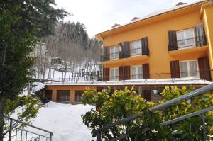 ein gelbes Gebäude mit Schnee davor in der Unterkunft Hotel Sport in Sestola