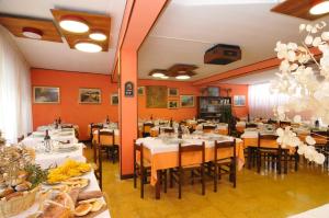a restaurant with white tables and chairs and orange walls at Hotel Sport in Sestola