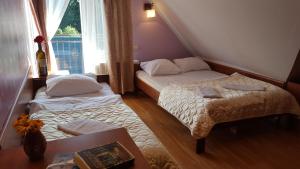 a bedroom with two beds and a table and a window at Gościniec Kukle in Kukle