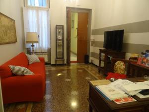 a living room with a red couch and a tv at Albergo Locanda Alambra in Genoa