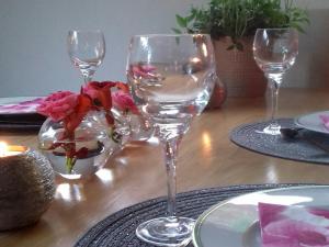 a table with two wine glasses and a vase of flowers at La Maison D'ayona in Herrlisheim-près-Colmar