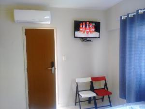 Pokój z 2 krzesłami i telewizorem na ścianie w obiekcie Pousada Itararé w mieście Campina Grande