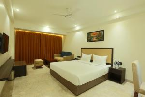 马图拉Centrum Hotel by Brijwasi的卧室里有一张白色的大床和一张书桌 更多11张照片
