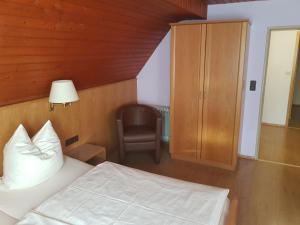 een slaapkamer met een bed en een stoel bij Pension Zum Grünen Wald in Feuchtwangen