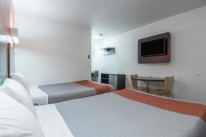 um quarto de hotel com duas camas e uma mesa com uma televisão em Motel 6 Bakersfield em Bakersfield