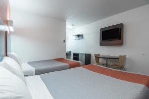 a hotel room with two beds and a table with a tv at Motel 6 Bakersfield in Bakersfield