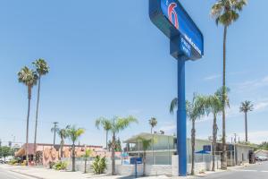 a blue street sign on a street with palm trees at Motel 6 Bakersfield in Bakersfield