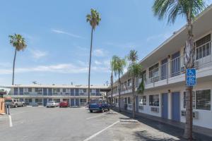 um parque de estacionamento em frente a um edifício com palmeiras em Motel 6 Bakersfield em Bakersfield