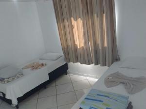 two twin beds in a room with a window at Hotel Dal Gobo in Ponta Grossa