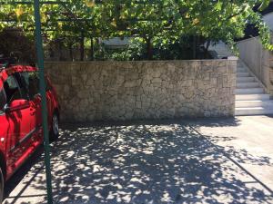 a stone wall and a red car parked next to a fence at Villa Conte in Korčula