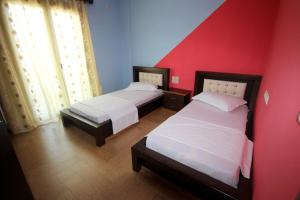 two beds in a room with red and blue walls at Mihal Suites in Sarandë