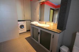 a bathroom with a sink and a washing machine at Mihal Suites in Sarandë