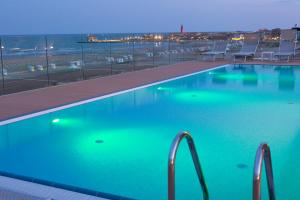 a swimming pool with a view of the ocean at night at Hotel Monaco in Caorle