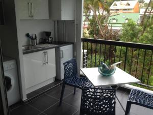 a kitchen with a table and chairs on a balcony at Studio Bas du Fort Guadeloupe in Le Gosier