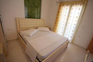 a bedroom with a white bed with a window at Mihal Suites in Sarandë