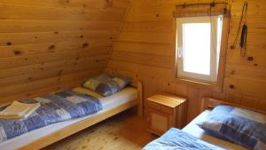 two beds in a log cabin with a window at Domki nad Soliną in Olchowiec