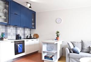 グディニャにあるGdynia4You Apartmentのキッチン(青いキャビネット、ソファ付)