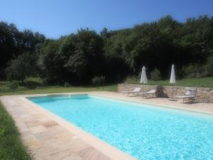 a blue swimming pool with two chairs and umbrellas at Il Giardino Di Rosmarino in Pontremoli