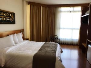 a hotel room with a bed and a window at Serema Palace Hotel in Lavras