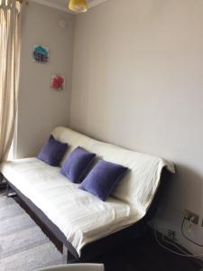 Una cama en una habitación con almohadas moradas. en Departamento Viana, en Viña del Mar
